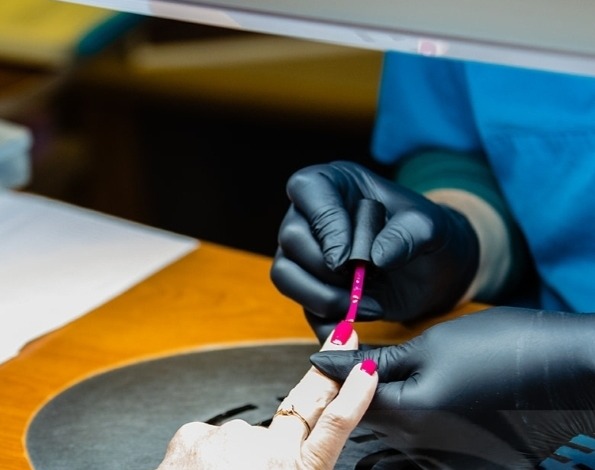 Gellac wordt met zwarte handschoenen aangebracht aan de werktafel