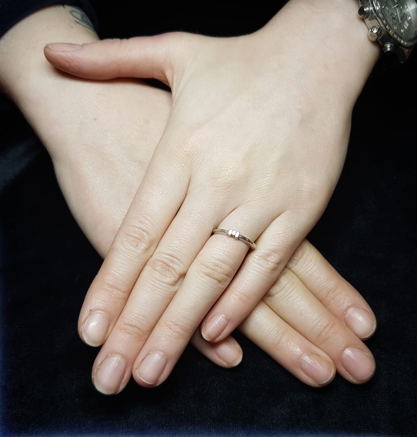 Verzorgde natuurlijke nagels in een zachte nudetint, handen over elkaar