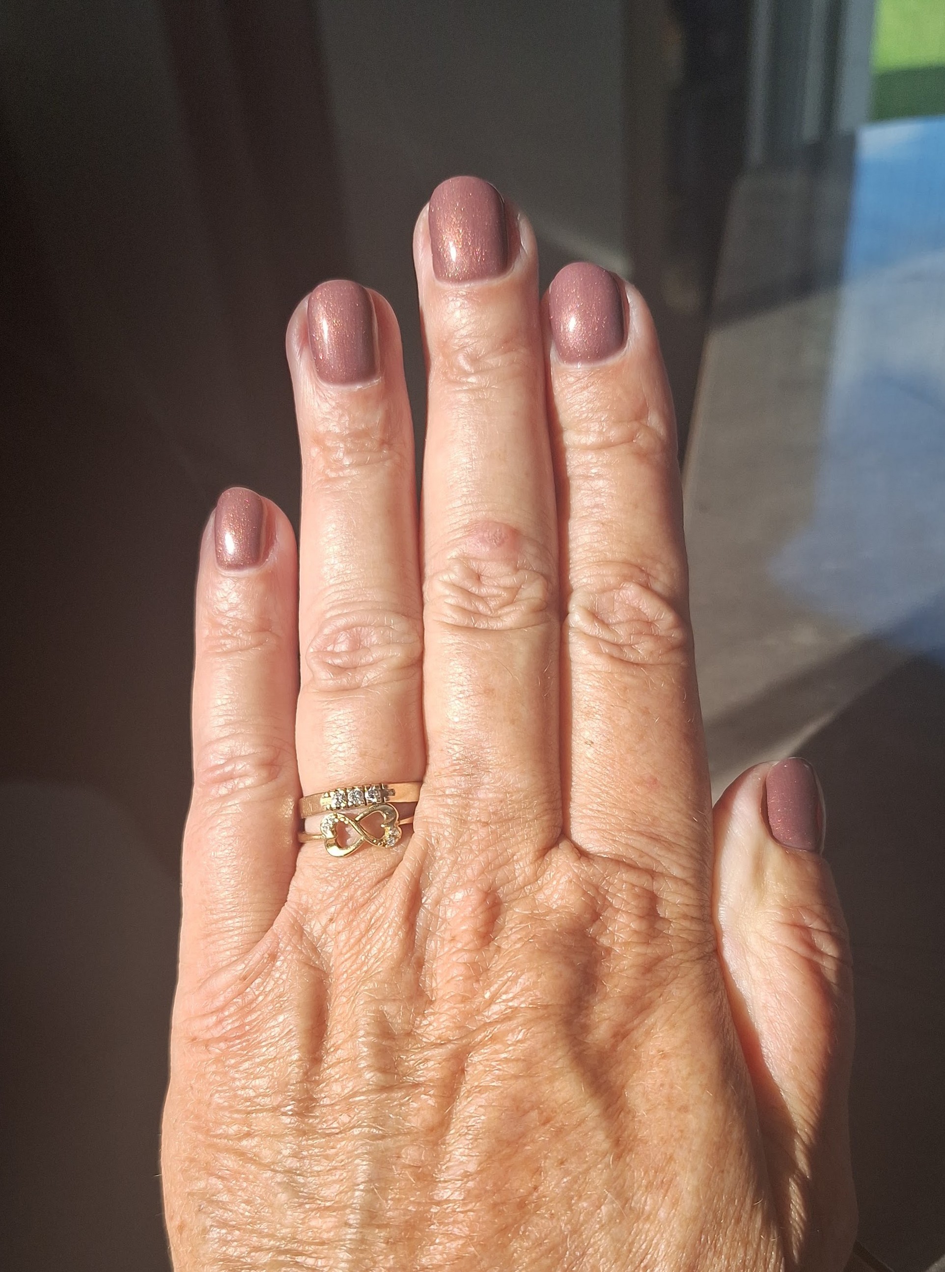 Hand met mauve gellac voor een raam