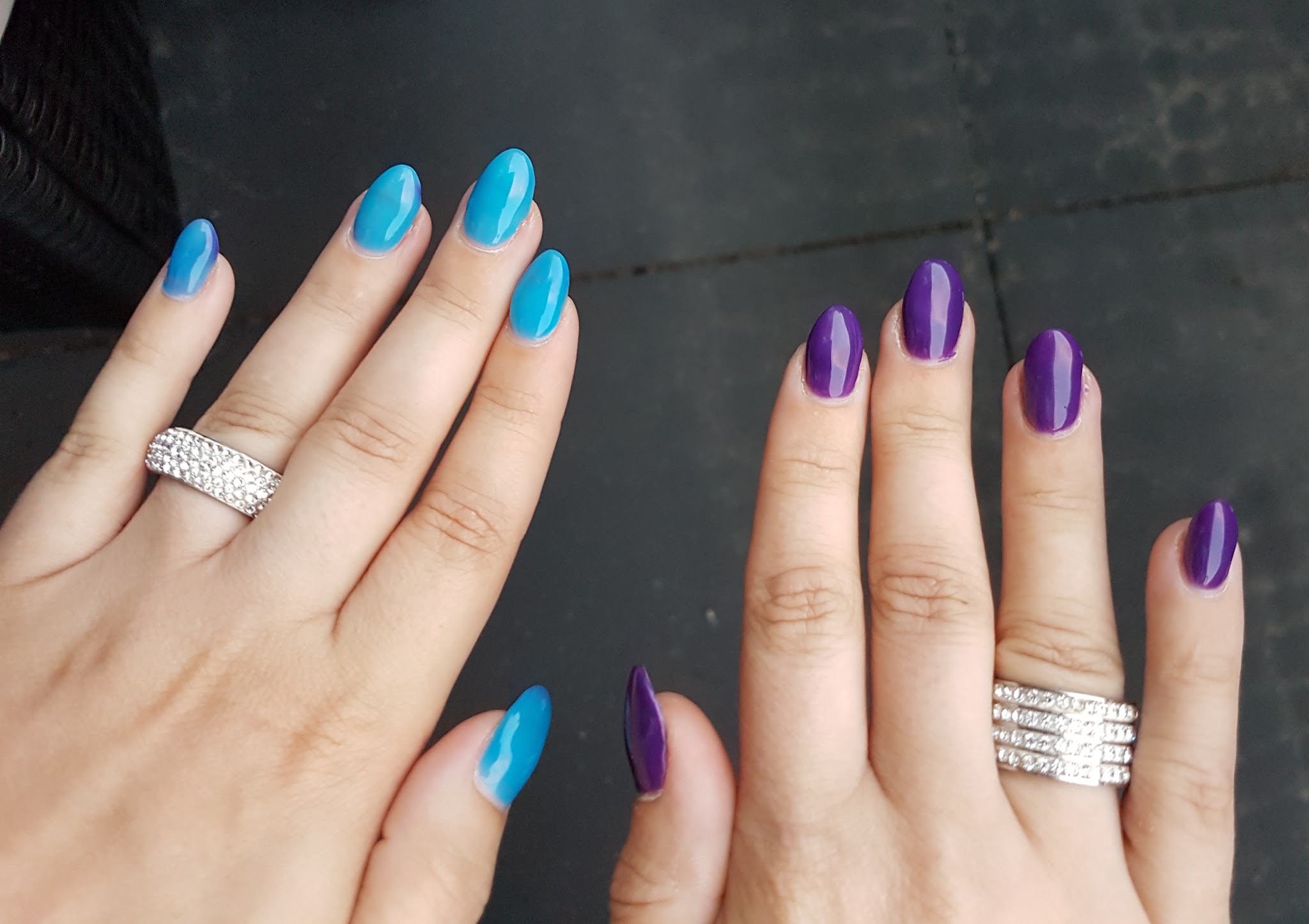 Twee handen, de ene met felblauwe en de andere met paarse gellac